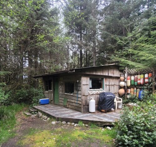 The Agate — a small cedar-shake bungalow in a forest hollow hung with beachcombed floats