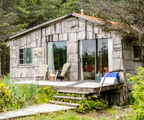 The Waldorf — a cedar-shake cabin with a wall of glass doors opening onto its deck